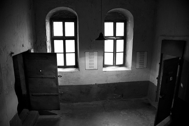 Corredor lúgubre con puertas abiertas enfrentadas y ventanas con arco, evocando el ambiente opresivo de La Comisaría de los Muertos, un relato sobre represión y muerte bajo custodia.